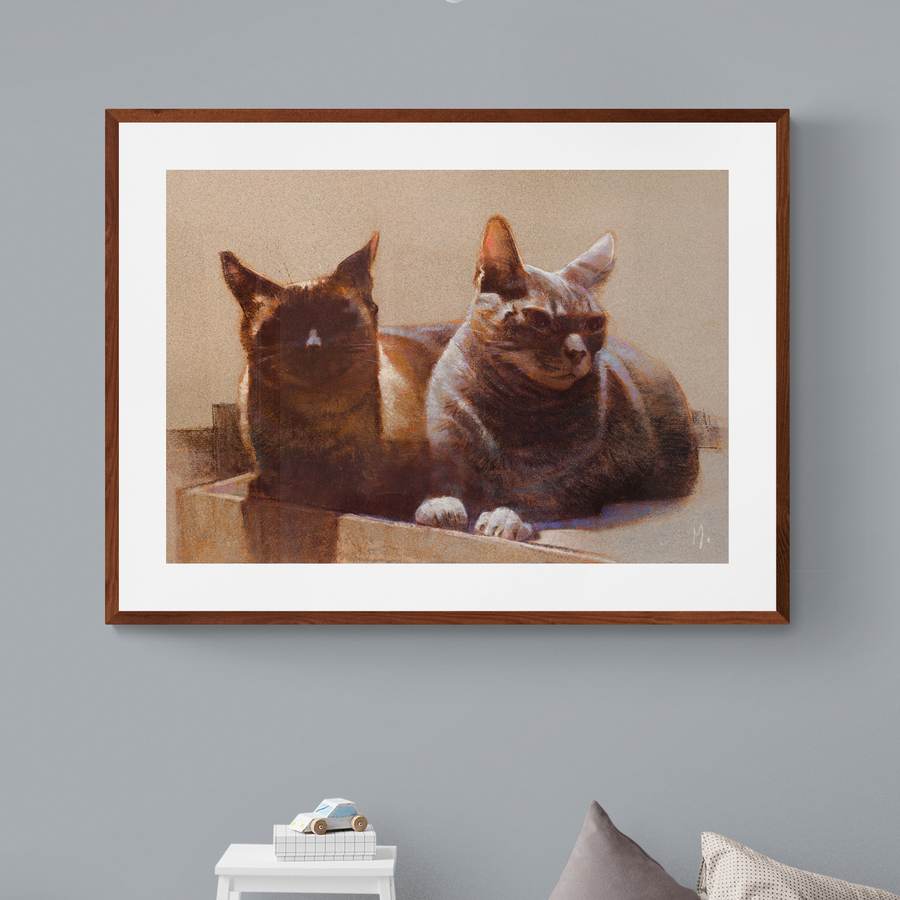 Retrato de dois gatos emoldurado em parede clara de um quarto infantil.