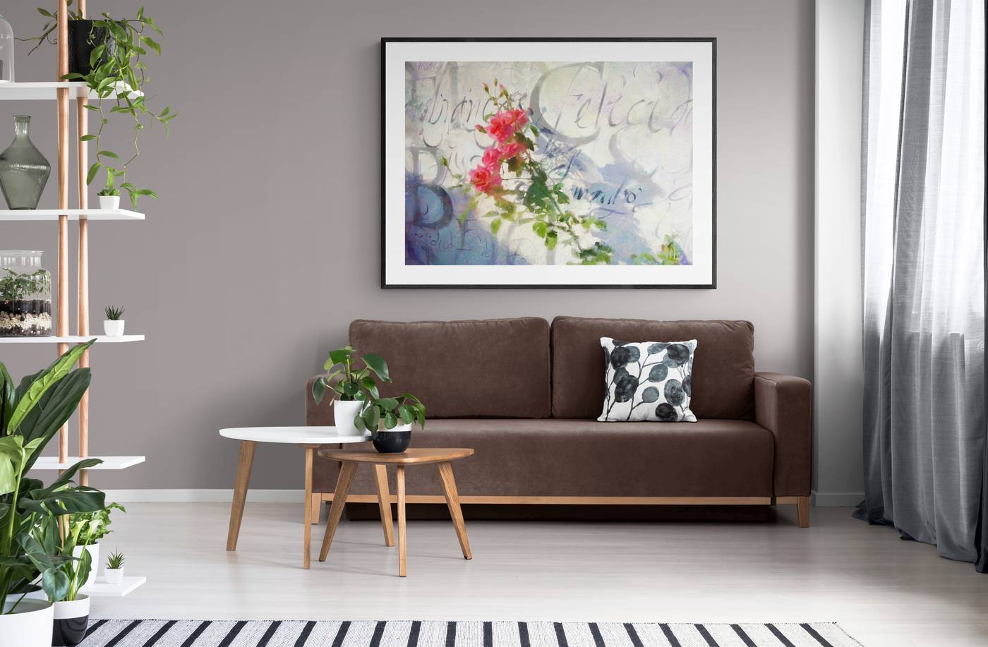A pintura das rosas emoldurada, pendurada acima de um sofá marrom em uma sala clara com plantas.