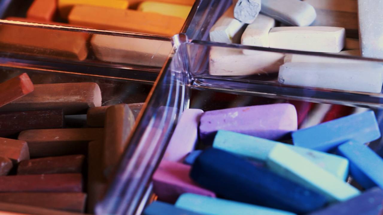 Caixa de bastões de pastel seco em várias cores, vista de perto.